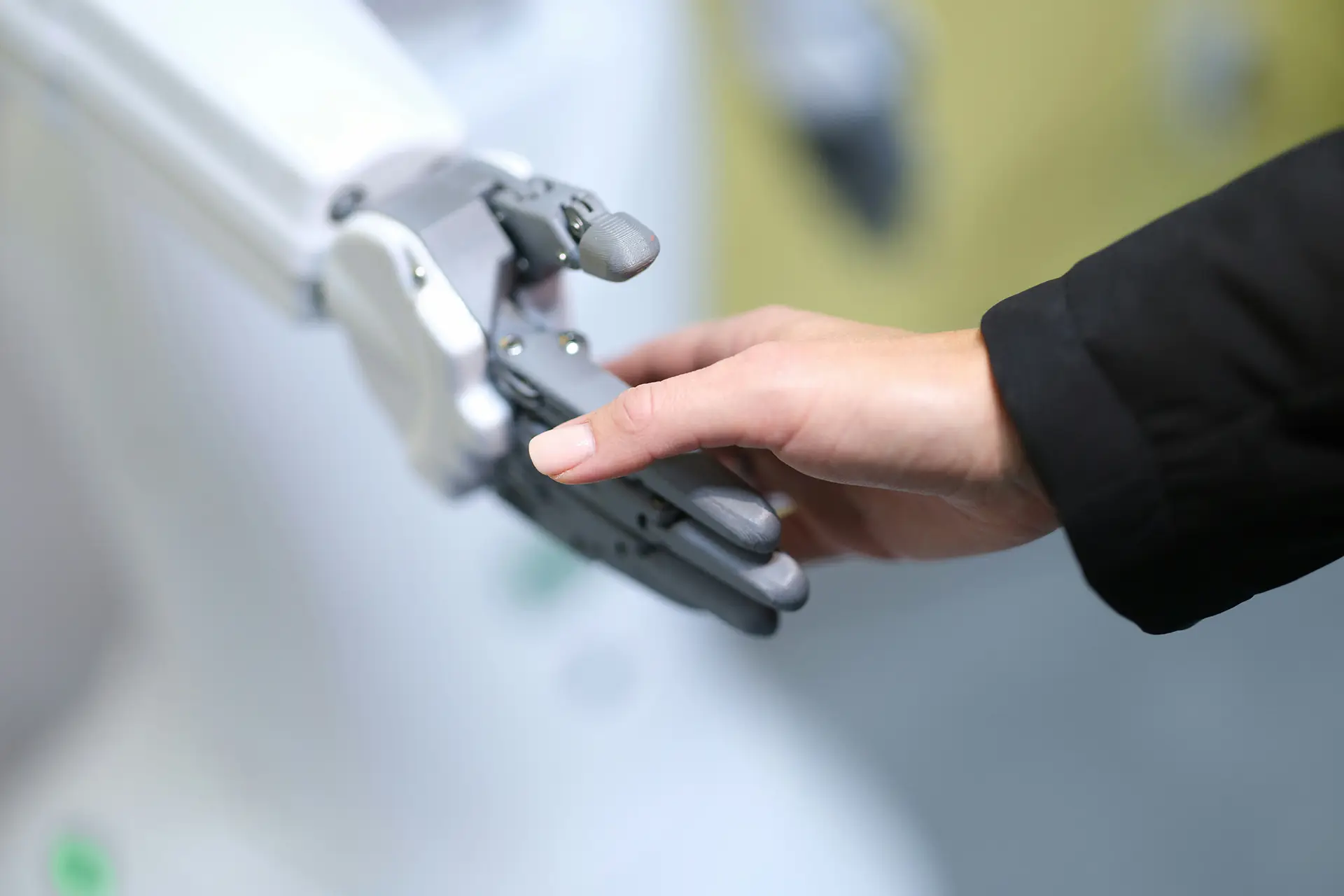 Human hand and robotic hand reaching out to touch each other in a close up view.